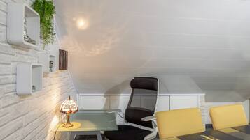 Ein stilvolles Zimmer mit Glastisch, zwei Stühlen, einer Lampe und einer Pflanze.