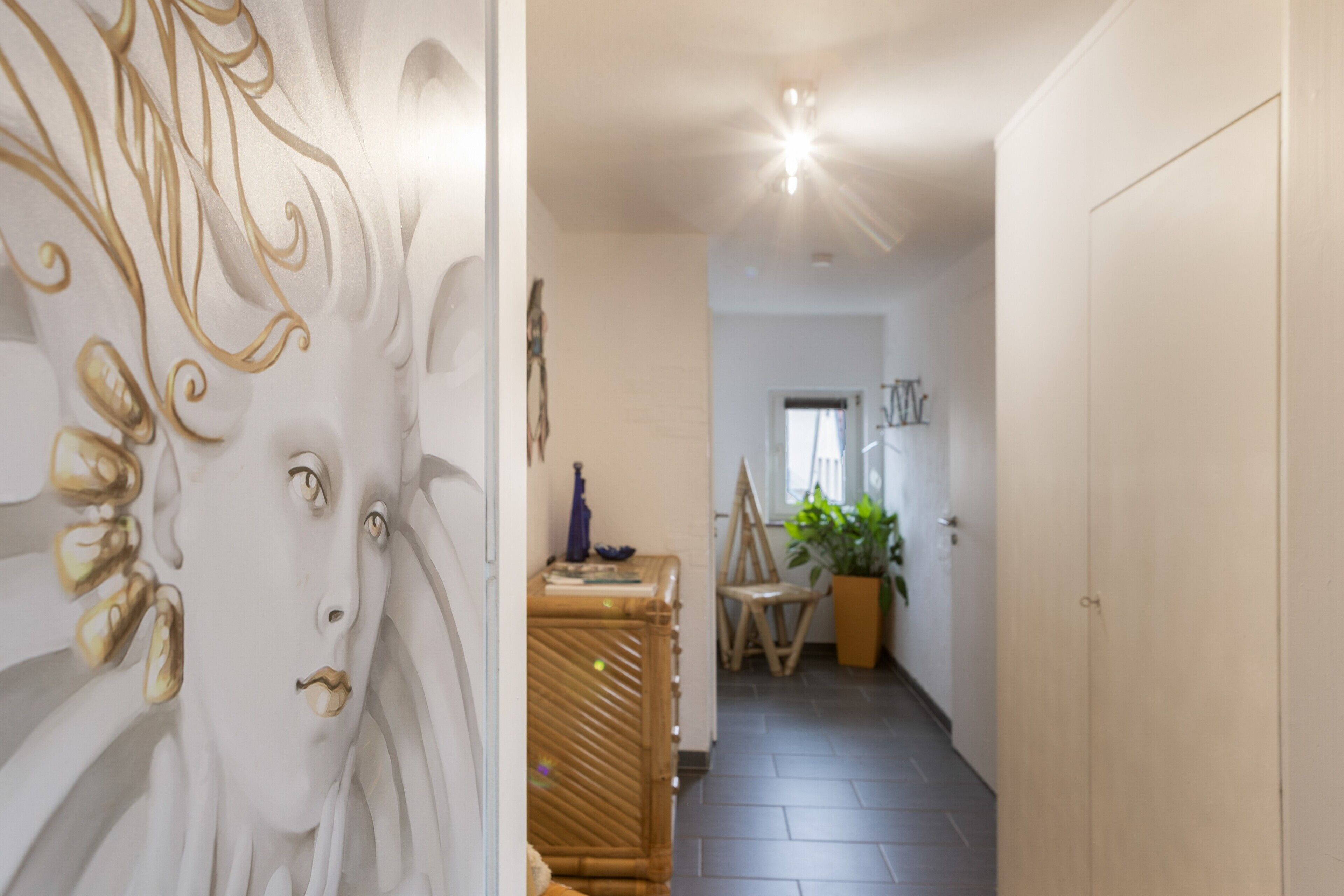 Een gang met decoratieve wanden, een houten kast, een stoel en een potplant.