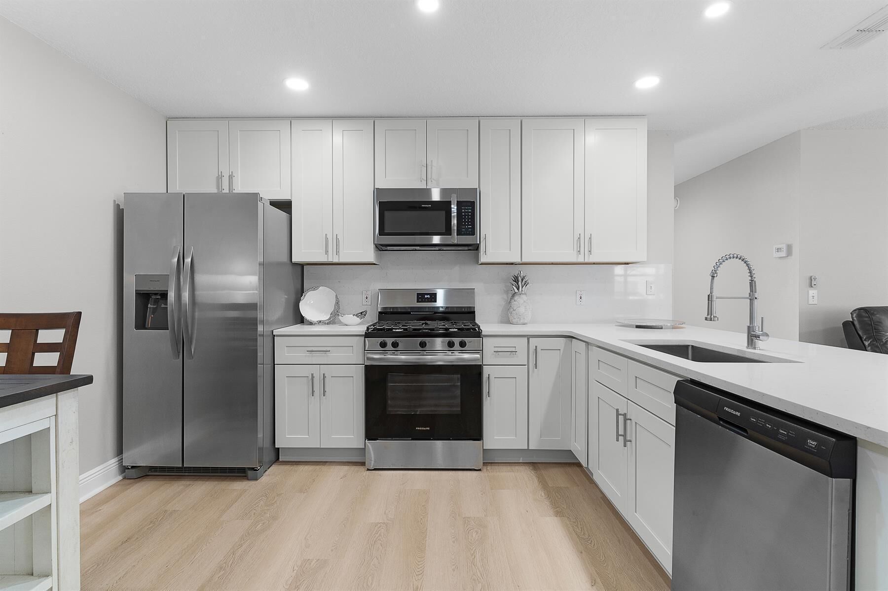 Una cocina moderna con armarios blancos, electrodomésticos de acero inoxidable y lavavajillas.