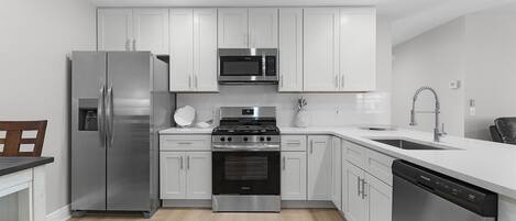 Una cocina moderna con armarios blancos, electrodomésticos de acero inoxidable y lavavajillas.