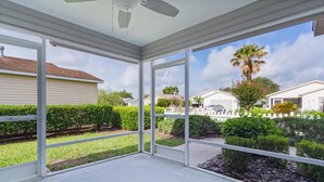 A covered patio with large windows overlooking a residential area.