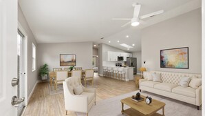 A spacious living area with a sofa, coffee table, and chairs, a dining area with a table and chairs, and a kitchen with modern appliances.