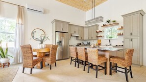 A modern kitchen with a central island, built-in appliances, and wicker chairs. - Rustic Elegance Farmhouse for a tranquil retreat experience in Sanford, FL (Sanford)