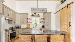 A modern kitchen with a central island, built-in appliances, and a large wooden door. - Rustic Elegance Farmhouse for a tranquil retreat experience in Sanford, FL (Sanford)