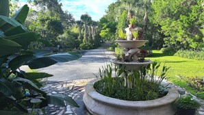 A garden with a central fountain, surrounded by lush greenery and a paved walkway. - Rustic Elegance Farmhouse for a tranquil retreat experience in Sanford, FL (Sanford)
