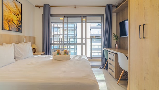 Une chambre d’hôtel moderne, dotée d’un grand lit, d’un bureau et d’une télévision.