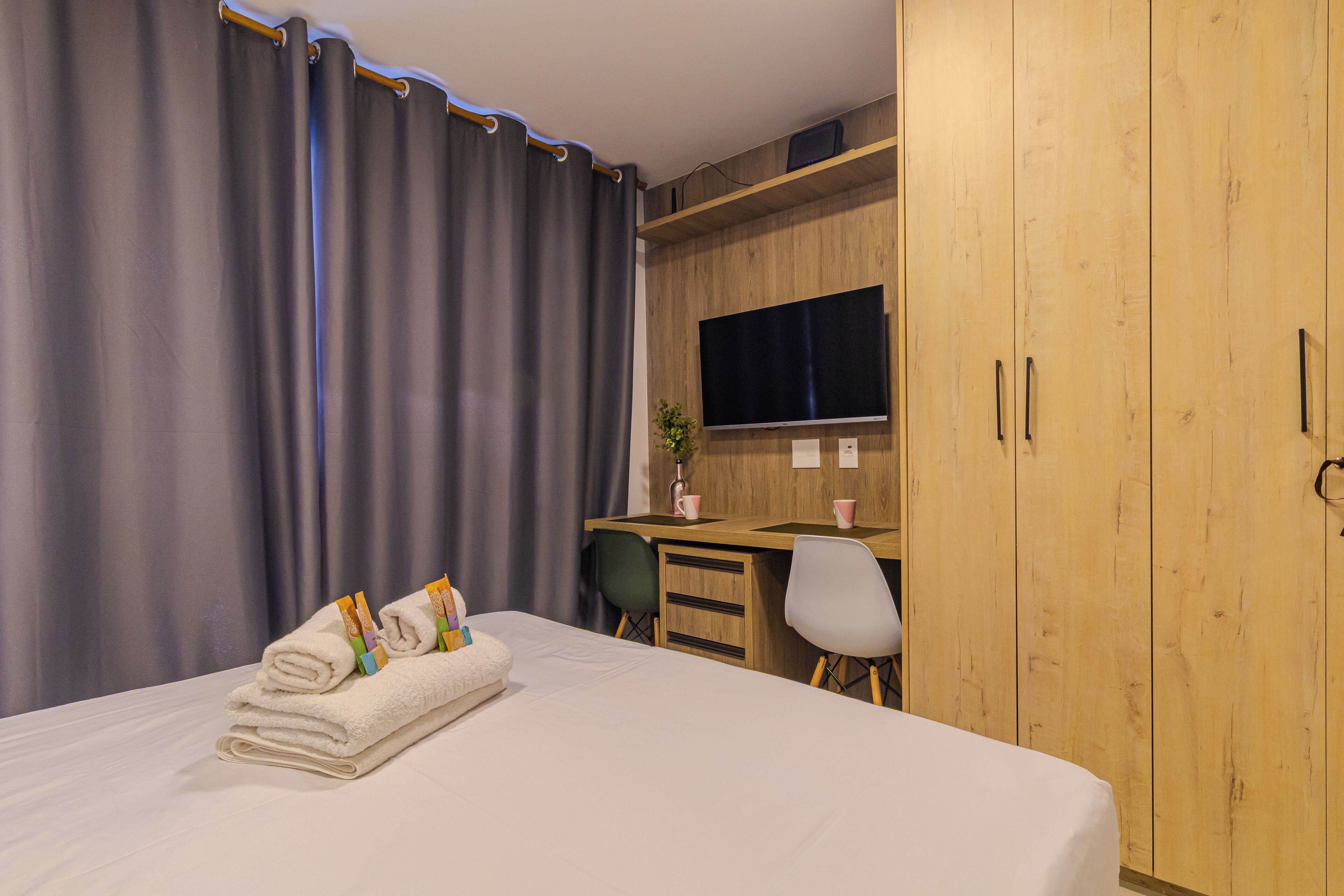 A hotel room with a bed, a desk, a chair, and a wardrobe.
