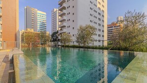 Une piscine à l’eau claire, entourée d’immeubles et d’arbres.
