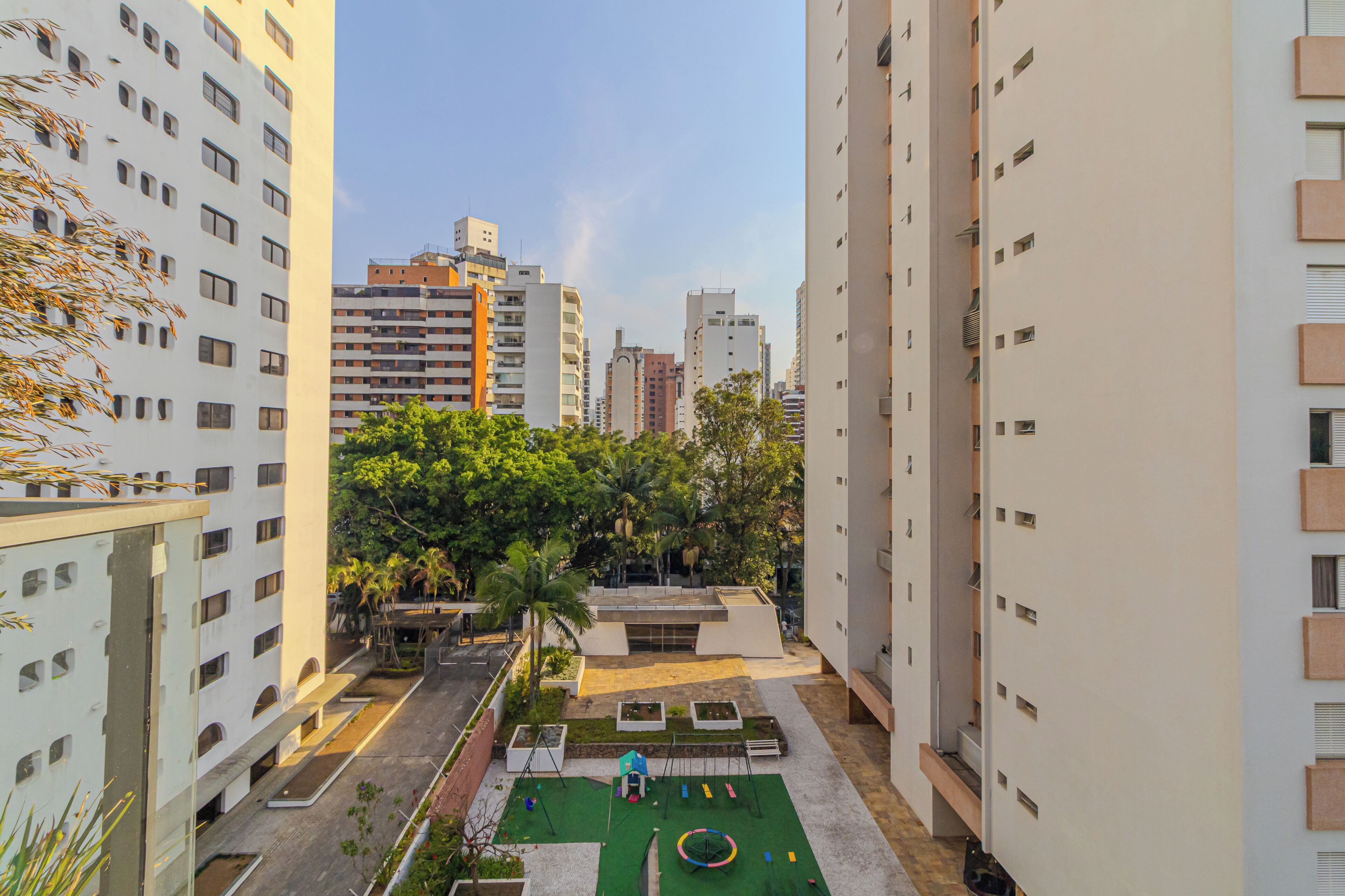 A high-rise building with multiple floors, a courtyard with greenery, and a playground area.