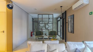 Un hall d’hôtel moderne avec un espace salon, un extincteur et un panneau de sortie vert.