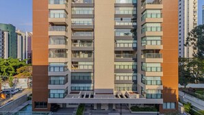 Un immeuble moderne de grande hauteur, doté de nombreux balcons et d’une cour intérieure.