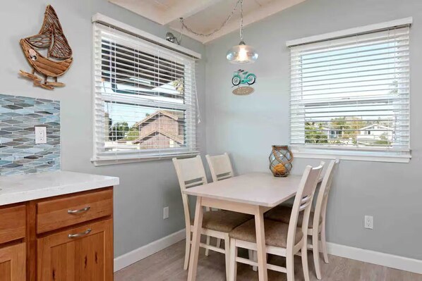 Una cocina con una mesa de comedor, sillas, armarios de madera y un elemento decorativo en la pared.