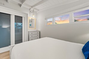 Une chambre à coucher avec un lit, une commode, un miroir et une porte coulissante.