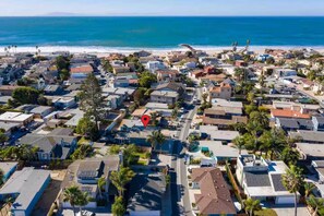 Vista aérea de una zona residencial costera con casas, caminos y una playa.