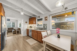 A modern kitchen with wooden cabinets, a white countertop, and a large window with a view.