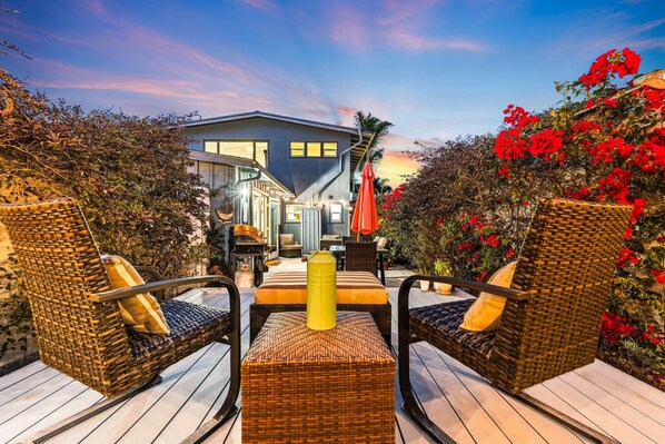 Une maison moderne dotée d’une terrasse avec des meubles en osier et un objet cylindrique jaune.