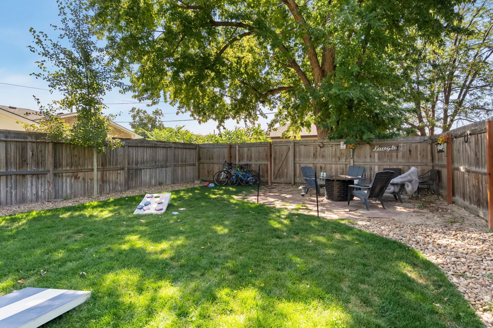 A backyard with a wooden fence, a grill, a table, and a bicycle.
