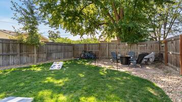 A backyard with a wooden fence, a grill, a table, and a bicycle.