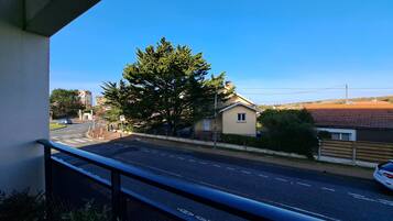 A balcony with a view of a road, a tree, and a building.