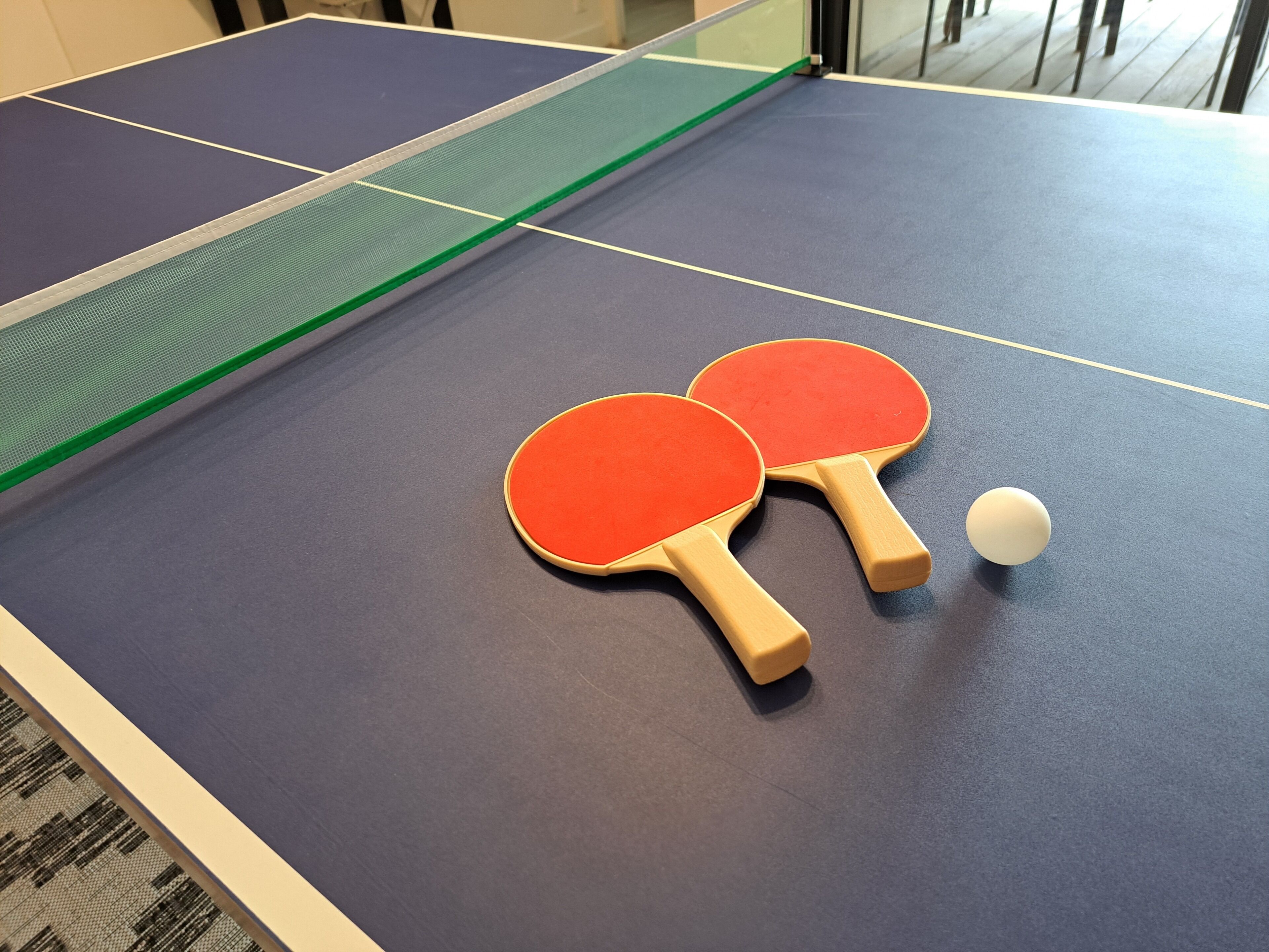 Ein Tischtennis-Tisch mit zwei Schlägern und einem Ball.