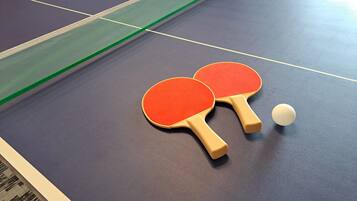 Ein Tischtennis-Tisch mit zwei Schlägern und einem Ball.