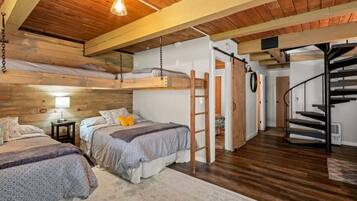 A cozy bedroom with two beds, a wooden ceiling, a ladder, and a spiral staircase.