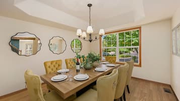 Une salle à manger avec une table en bois, des chaises recouvertes d’un tissu jaune et un lustre.