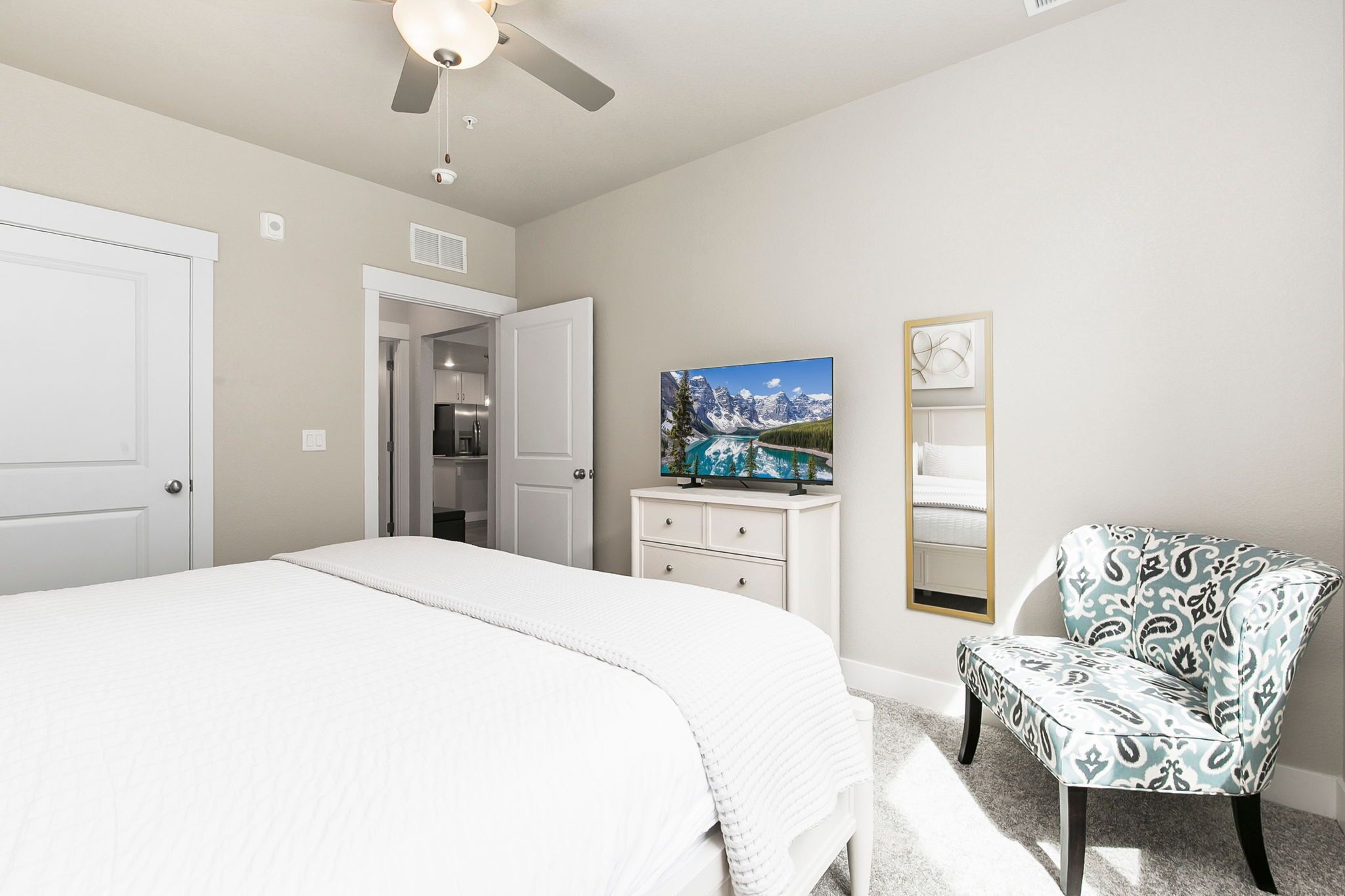 A bedroom with a large bed, a chair, a TV, and a painting on the wall.