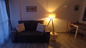 A cozy living area with a sofa, a lamp, a small table, and a TV. - Studio 'Benaldream' with Sea View, Shared Pool and Air Conditioning (Benalmádena)