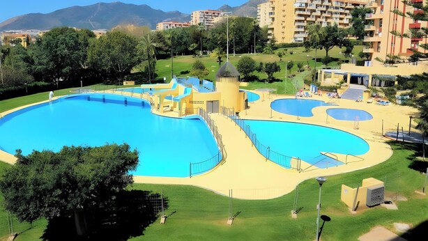 A large outdoor swimming pool with multiple sections, surrounded by greenery and residential buildings. - Studio 'Benaldream' with Sea View, Shared Pool and Air Conditioning (Benalmádena)