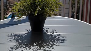 A balcony with a potted plant, a round table, and a view of buildings and the sea. - Studio 'Benaldream' with Sea View, Shared Pool and Air Conditioning (Benalmádena)