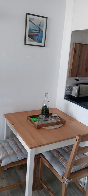 Un comedor con una mesa de madera, sillas, una bandeja con una botella y un cuadro en la pared.
