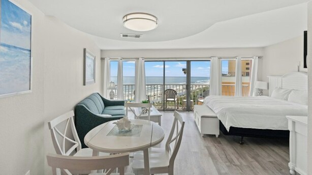 Une chambre d’hôtel moderne dotée d’un balcon, d’un lit, d’un coin repas et offrant une vue sur la mer.