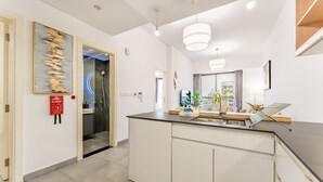 A modern kitchen with a central island, white cabinetry, and pendant lighting. - Near Circle Mall And Parks, Easy Access to Al Khail Road (Dubai)