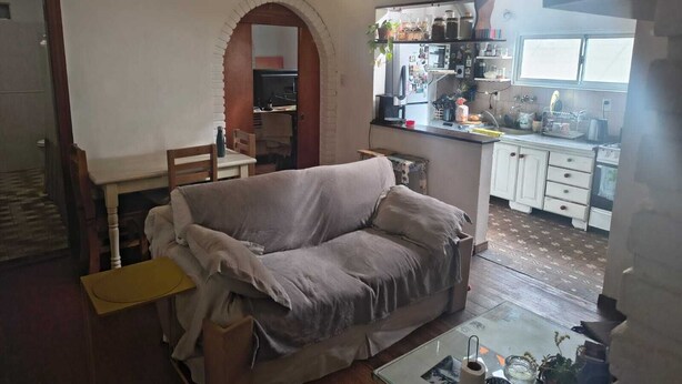 Una sala de estar acogedora con un sofá, una mesita y una zona de cocina con encimera y armarios.