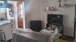 Un espacio habitable compacto con kitchenette, televisor y comedor.