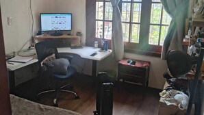 Una habitación pequeña y funcional con escritorio, ordenador, silla y cama.