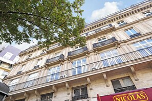 A multi-story building with classical architecture, featuring balconies with wrought iron railings. - Charming Studio - in the Heart of Paris/opera (Paris)
