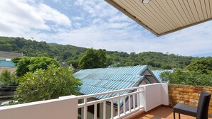 A balcony with a view of a green landscape and a building with blue roofs.