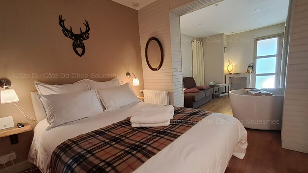 Ein Hotelzimmer mit einem großen Bett, einem Spiegel, einem Holz-Kopfteil, einem Nachttisch mit Lampe und Blick auf den Wohnbereich.