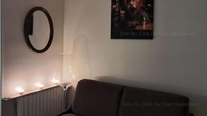 Ein gemütliches Zimmer mit einem dunkelbraunen Sofa, einem runden Spiegel und einem gerahmten Bild an der Wand.