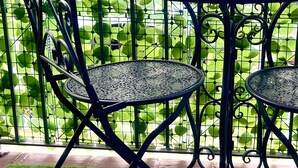 A metal table and chairs set against a green leafy background. - Studio 'Attilio's House' with Balcony, Wi-Fi and Air Conditioning (Capoterra)