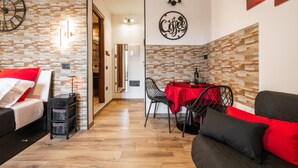 A modern living room with a sofa, a dining table with chairs, a coffee table, and a fireplace. - Studio 'Attilio's House' with Balcony, Wi-Fi and Air Conditioning (Capoterra)