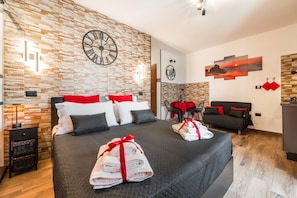 Une chambre d’hôtel avec un grand lit, une horloge murale, une œuvre d’art sur le thème du café, un canapé et un coin repas.