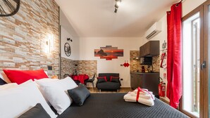 A hotel room with a bed, a sofa, a dining table, and a kitchen area. - Studio 'Attilio's House' with Balcony, Wi-Fi and Air Conditioning (Capoterra)