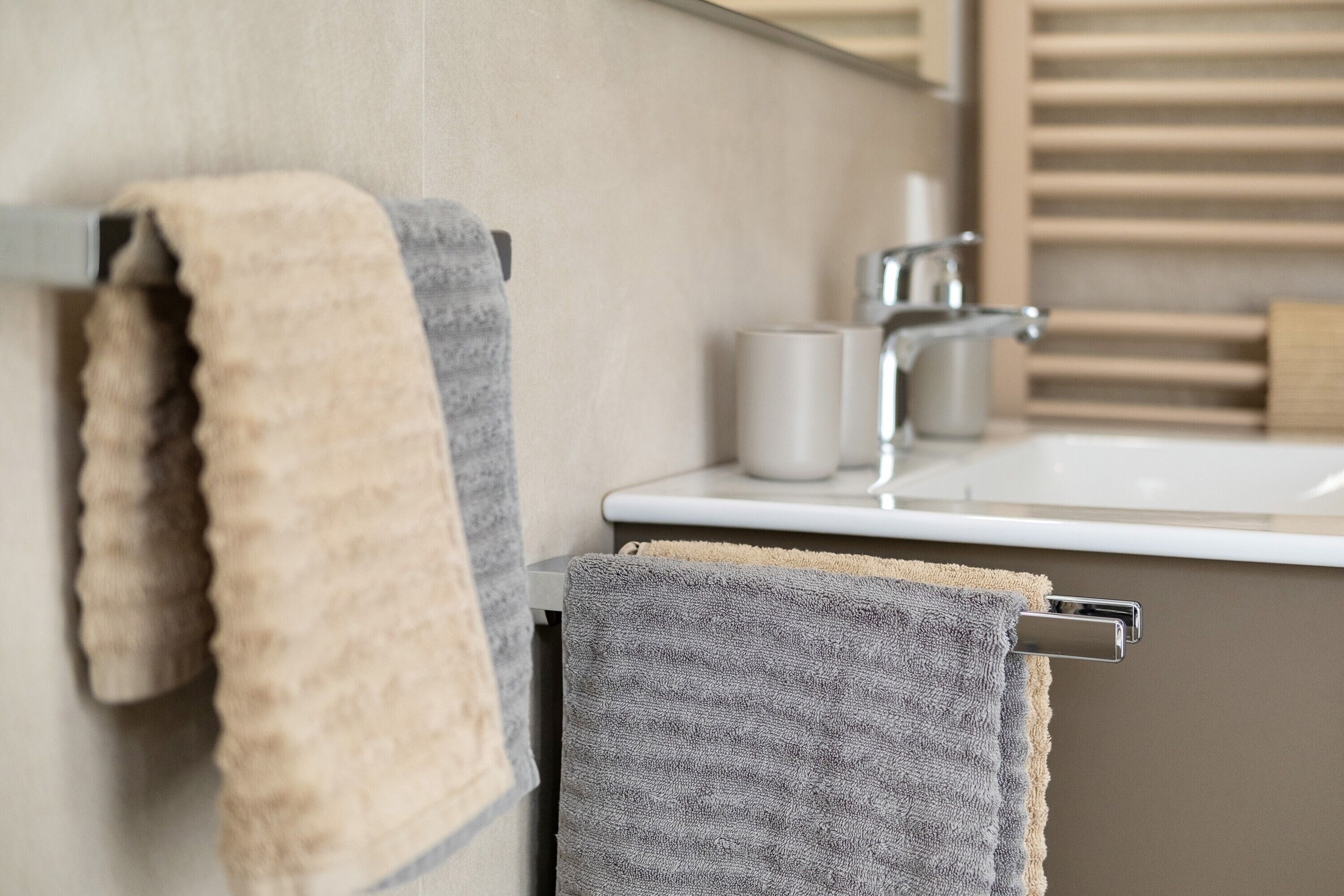 A bathroom with a towel rack holding two towels, a sink, and a mirror.