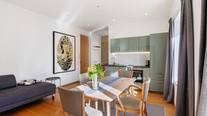 Un salon moderne avec un canapé, une table à manger, des chaises et une cuisine en arrière-plan.