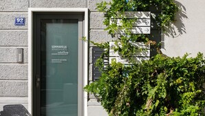 Une entrée d’immeuble avec une porte portant l’inscription « APPARTEMENTS SOMMAVILLA » et des panneaux indicateurs indiquant différentes directions.