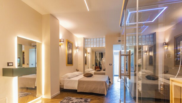 Una habitación de hotel moderna con dos camas, un separador de vidrio y suelo de mármol.