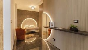 Un moderno vestíbulo de hotel con mostrador de recepción, un área de estar confortable y una lámpara circular grande.